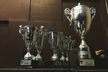 several silver and gold trophies on wooden surface